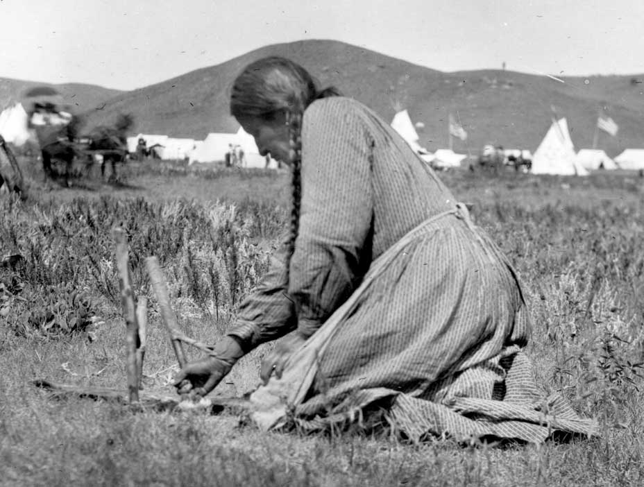 Sioux woman fleshing out a bison hide