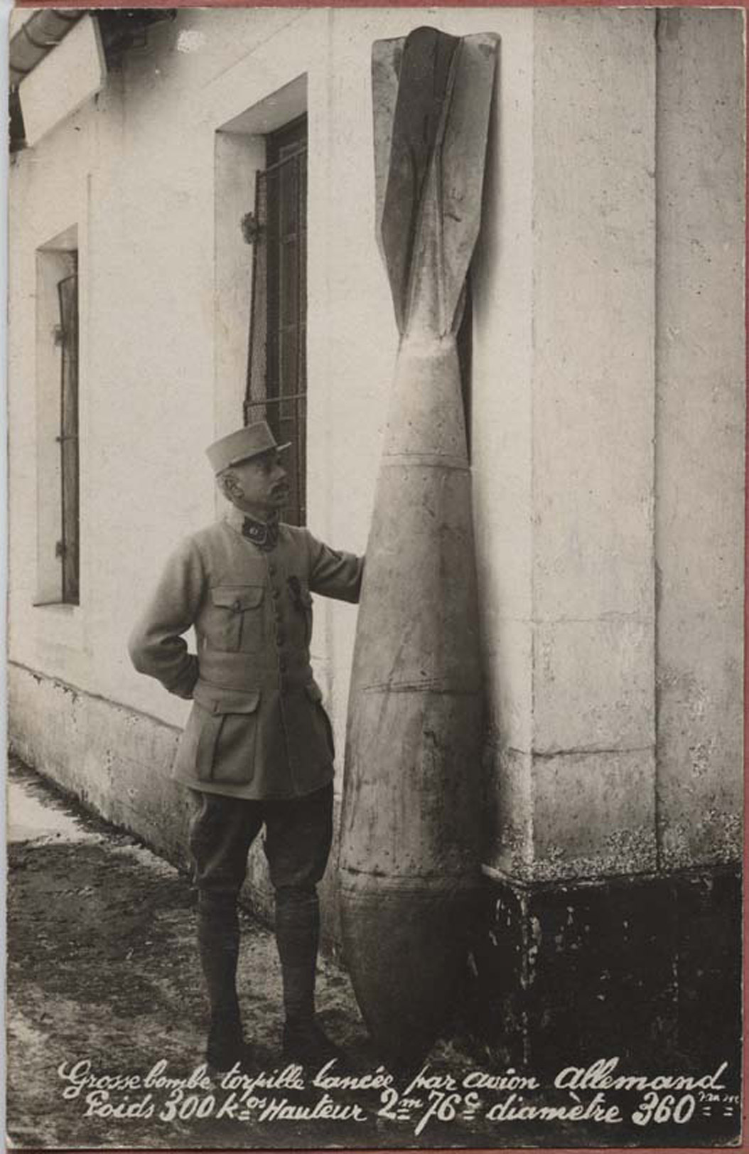 <span class='figure-reader-id'>Image 11:</span> 11086-27-03.  The bombs that fell on Nancy came in all kinds of shapes. In this photo, a soldier stands with this very large bomb. The fact that so many bombs did not explode helped to prevent much damage to the town. <span class='figure-archive-id'>SHSND 11086-27-03.</span>