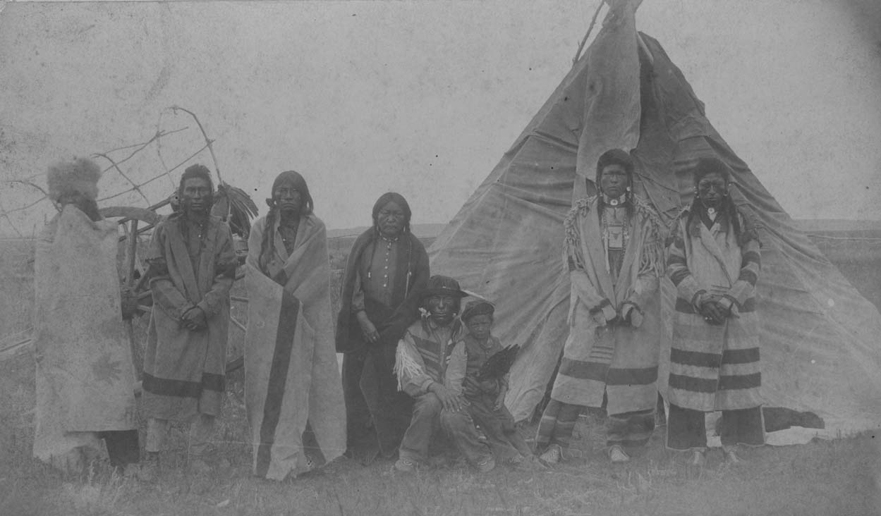 Cree Indians outside a hide tipi with a Red River oxcart nearby on the Fort Berthold Indian Reservation