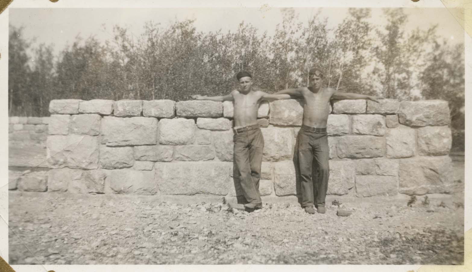 Two members of the Civilian Conservation Corps (CCC) Company 794 stand next to stone wall, International Peace Garden