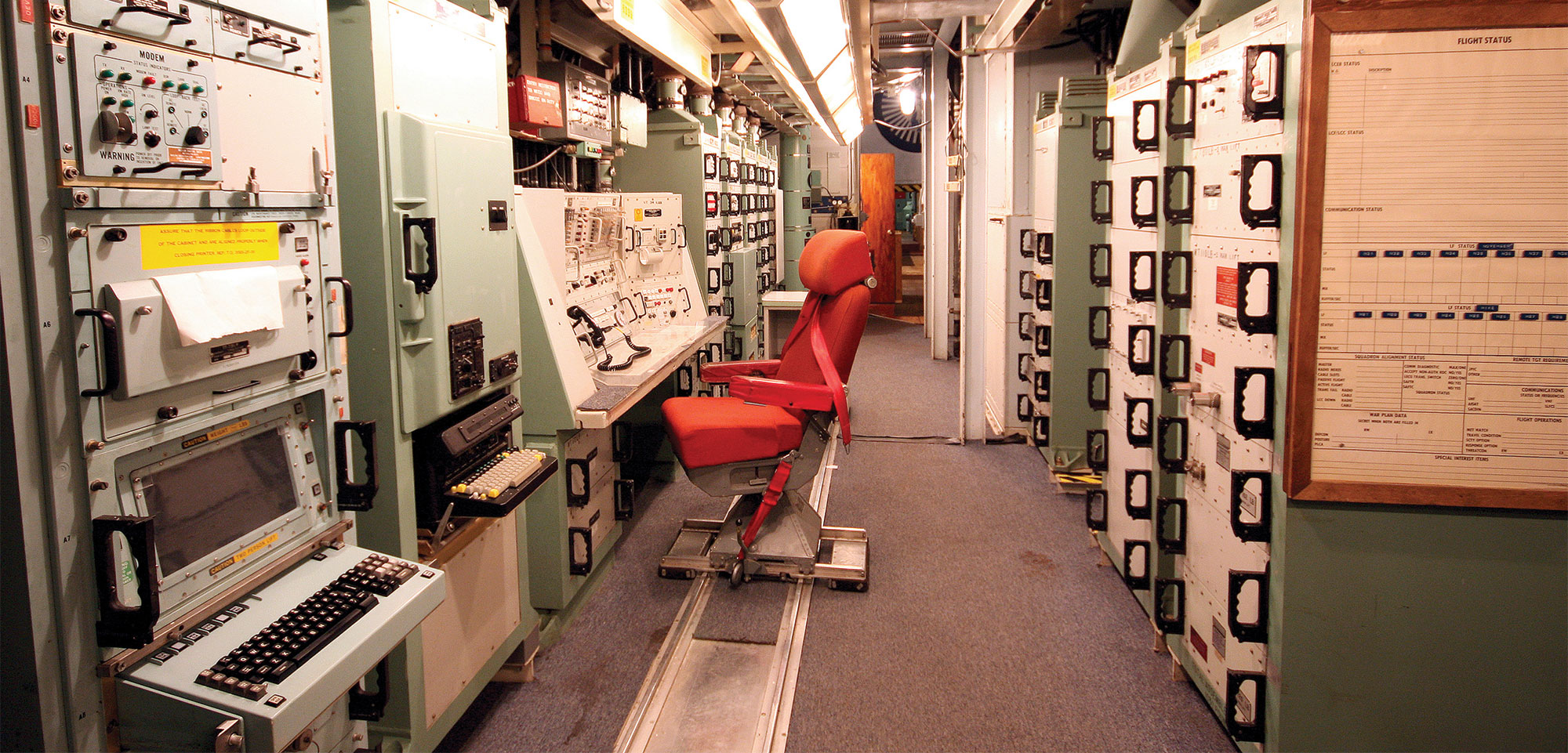 A red chair is shown sitting in the middle of walls of control panels